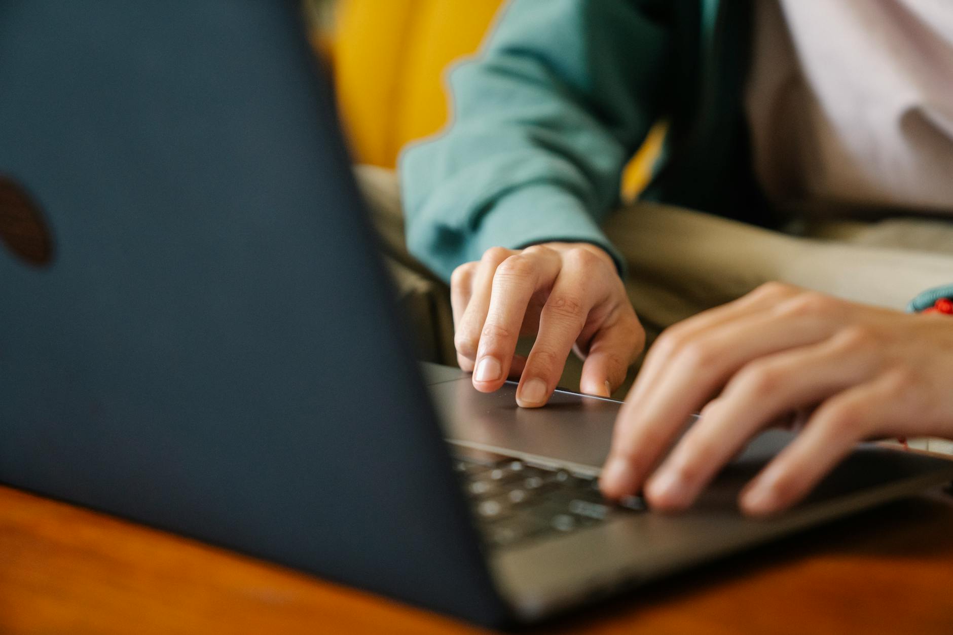 Crop unrecognizable distance employee surfing internet on netbook while working on project at desk in room — illustrating: Password managers explained without the tech jargon: what to know before picking one