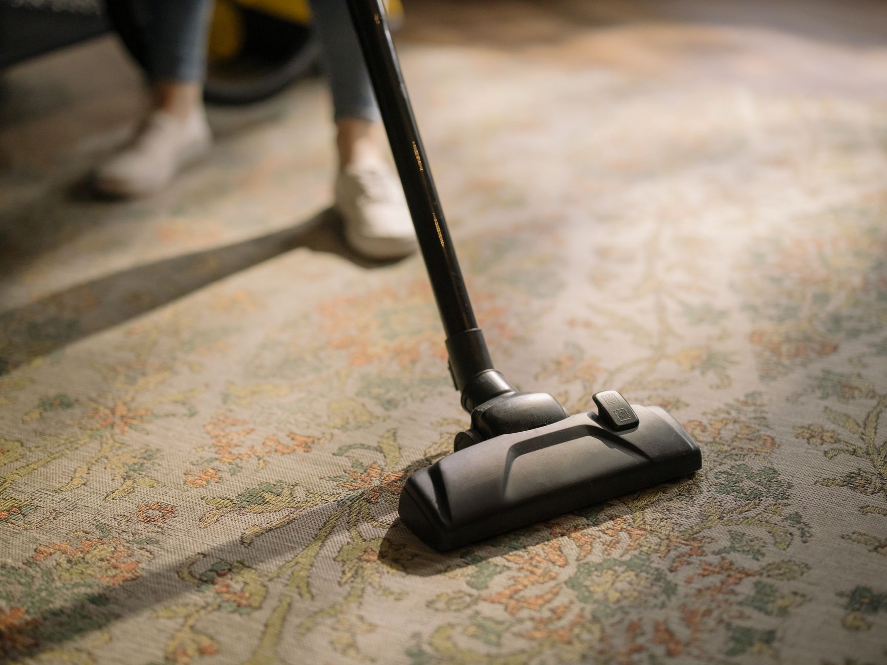Close-up of a vacuum cleaner on a patterned carpet in a sunlit room, capturing a moment of household cleaning — illustrating: The stick vacuum I’d actually recommend for families with shedding pets