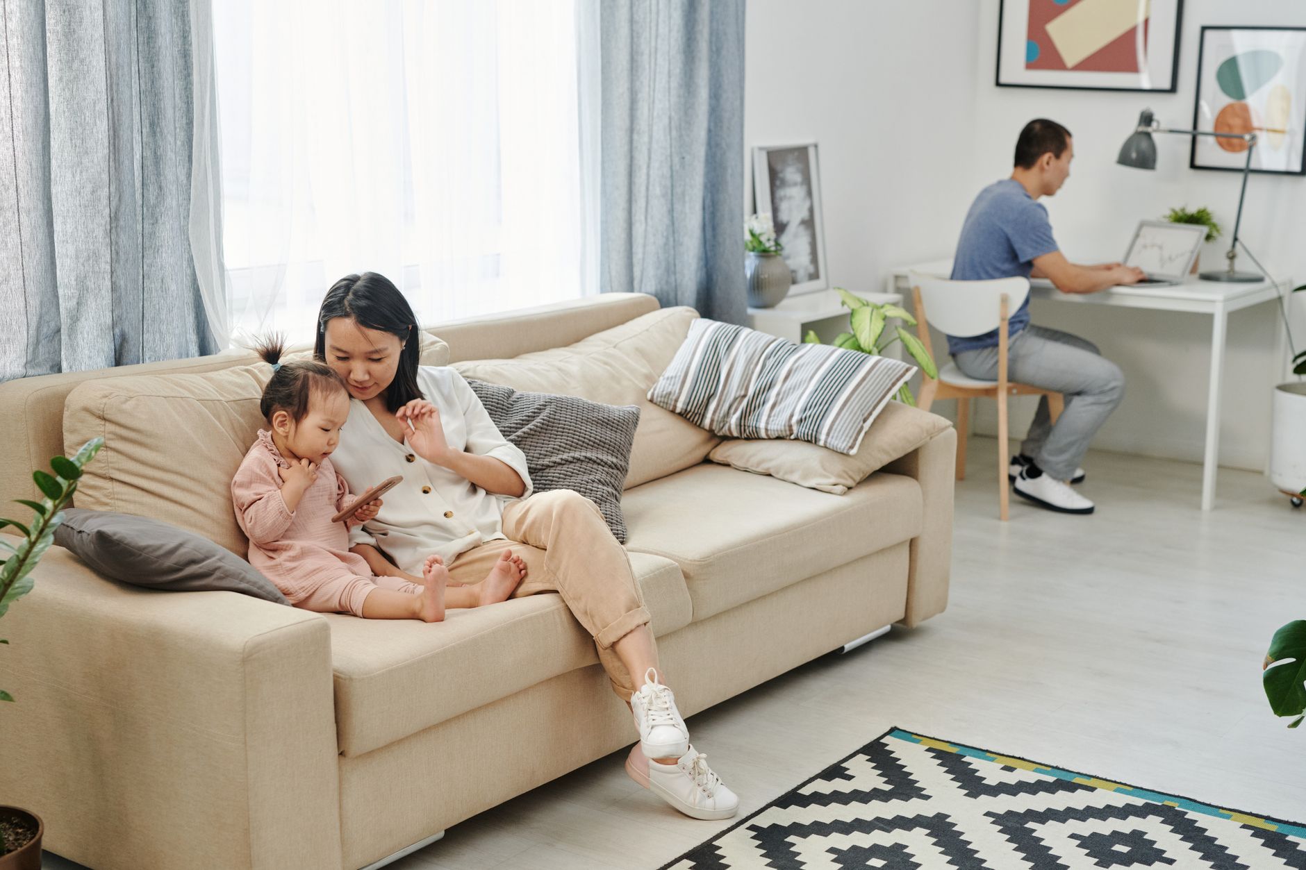 A mother and child bonding on a sofa while a man works on a laptop in a well-lit living room — illustrating: Photo editing software for non-experts: which tools are actually worth your time?
