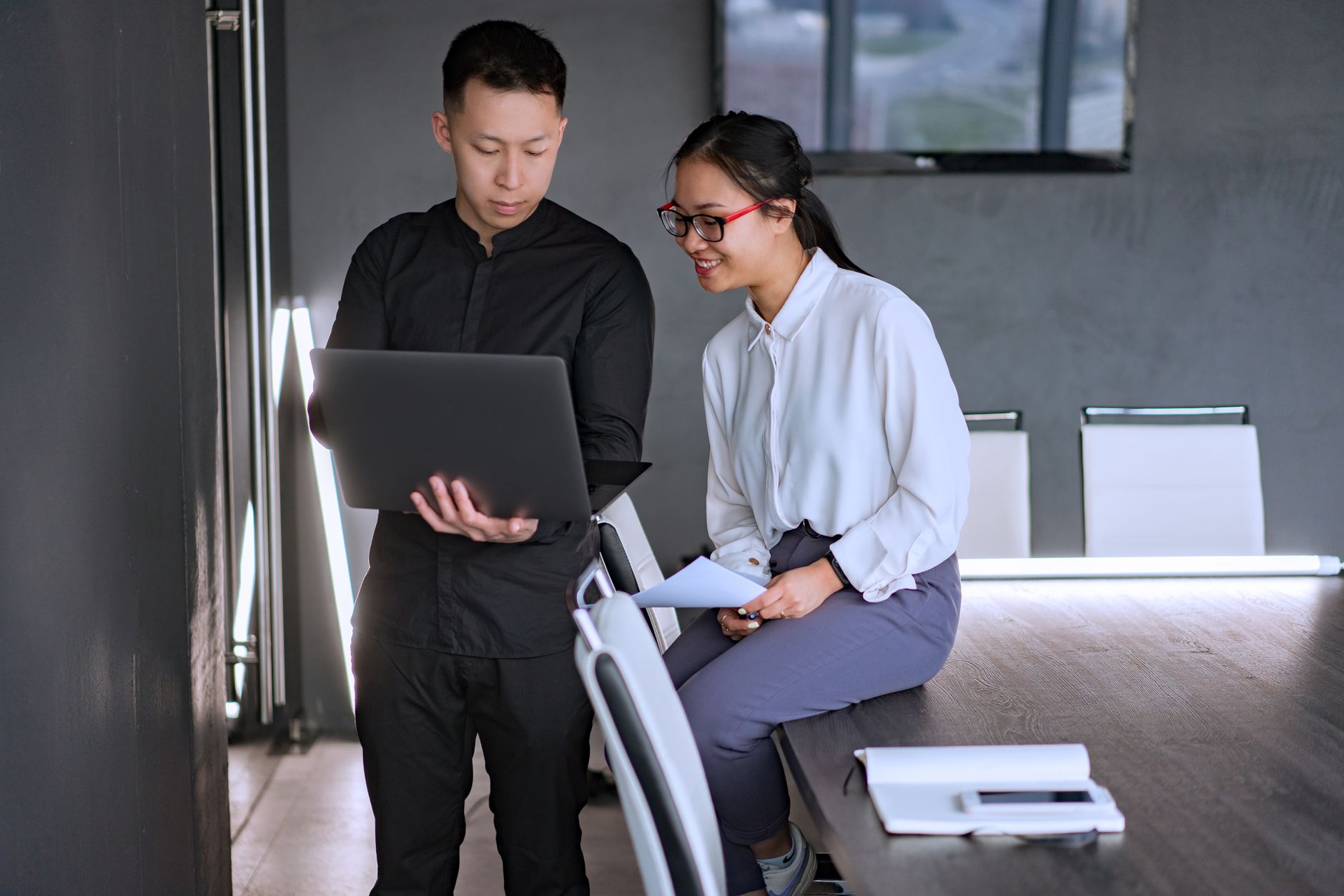 Two professionals collaborating in an office with a laptop, discussing documents and ideas — illustrating: Is this file backup software actually worth it for families? Here's what the reviews say about recovery speed
