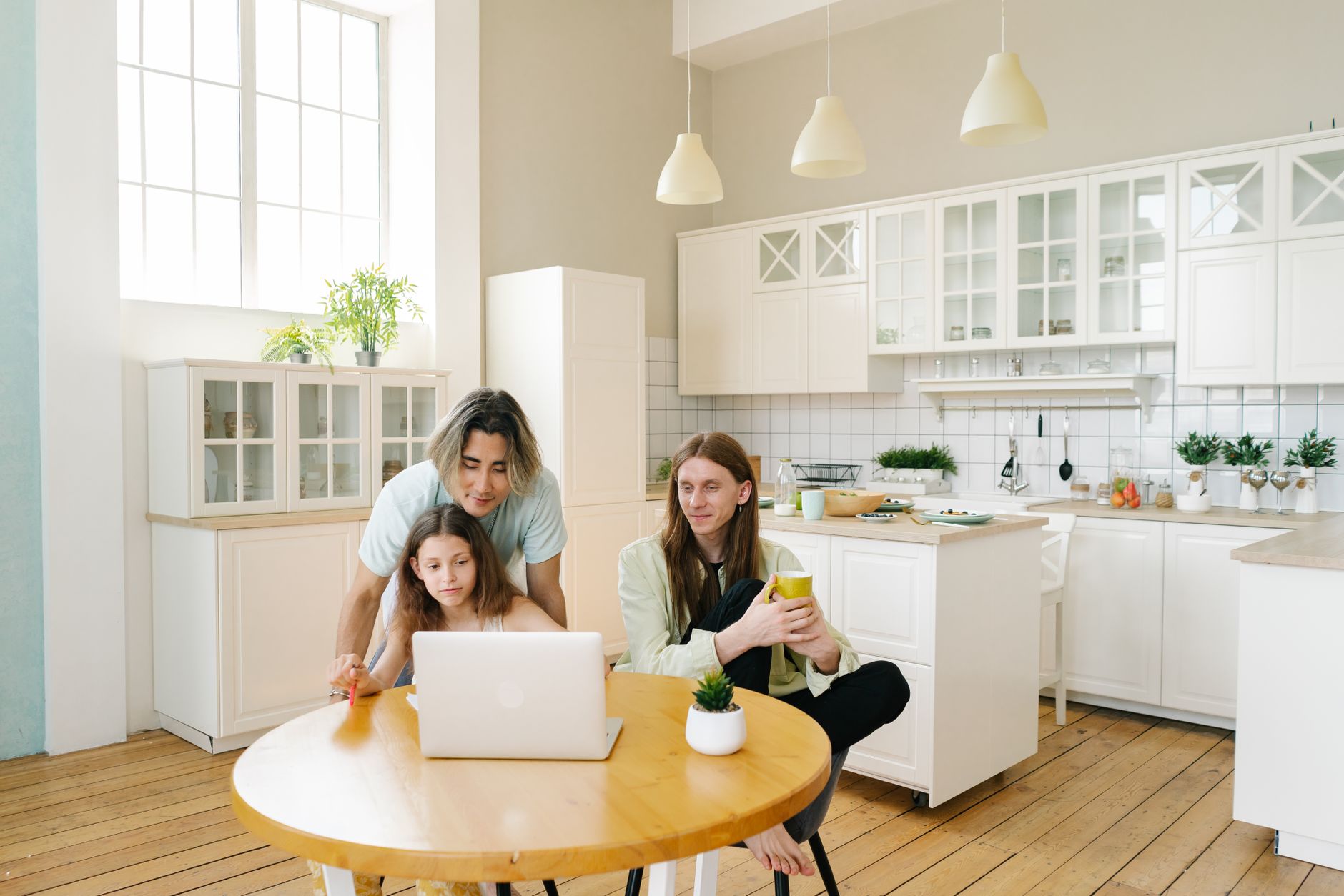 A family enjoys bonding time together in a bright, modern kitchen setting, using a laptop — illustrating: Cloud backup vs. external drives: which one actually makes sense for a family home computer?